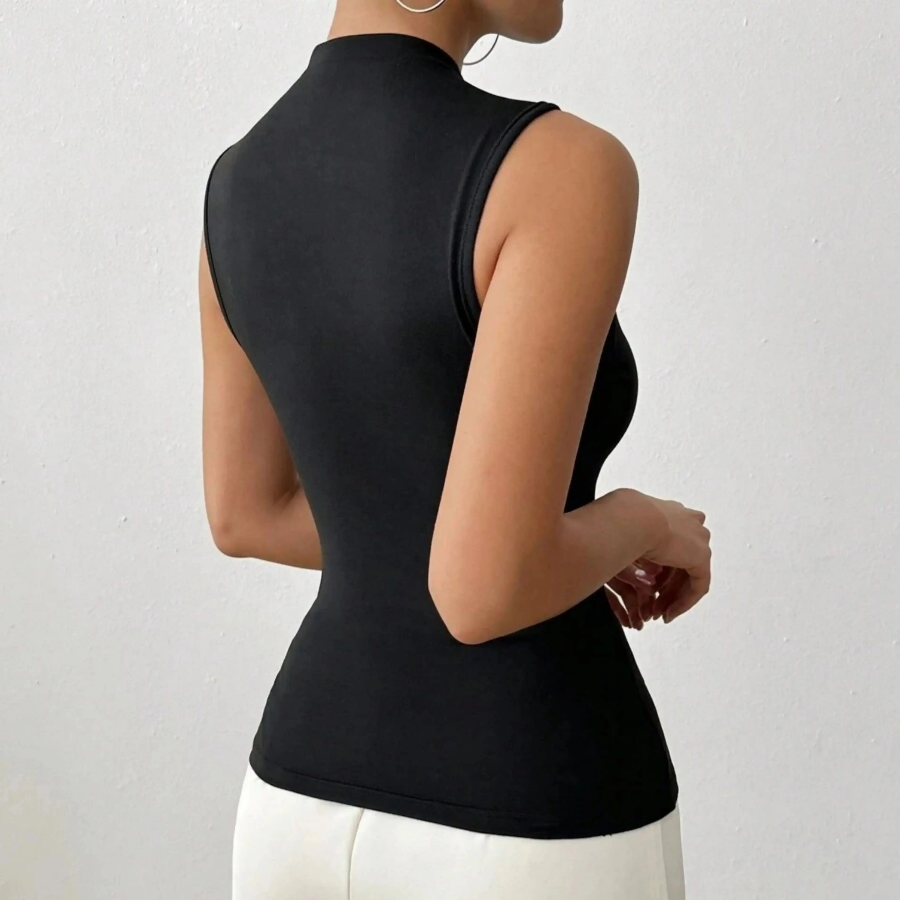 Person wearing a black sleeveless top against a white background
